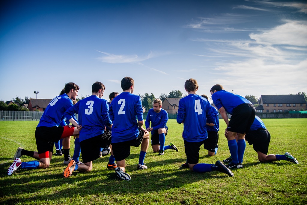 soccer players kneeling in blue uniforms on field